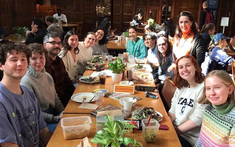 photo of 10 people gathered around a long wooden dining table